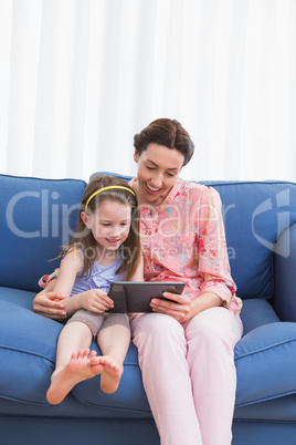 Mother and daughter using tablet on couch