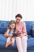 Mother and daughter using tablet on couch