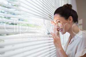 Woman peeking through the blinds