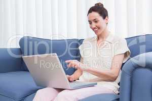 Casual brunette using laptop on couch