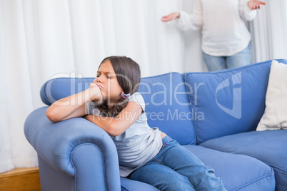 Angry little girl sitting on the couch