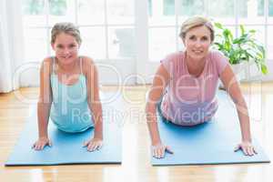 Happy mother and daughter doing yoga