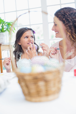 Happy mother and daughter painting easter eggs