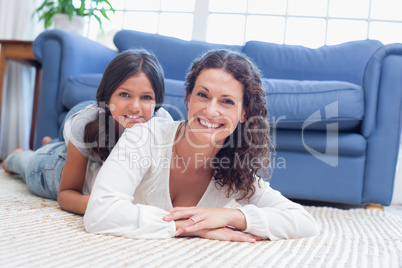 Happy mother and daughter lying on the floor