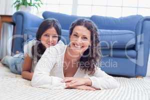 Happy mother and daughter lying on the floor