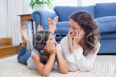 Happy mother and daughter lying on the floor