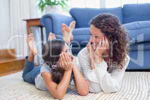 Happy mother and daughter lying on the floor