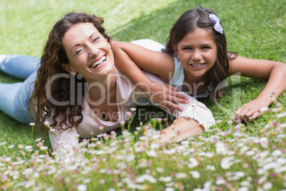 Happy mother and daughter lying on the grass