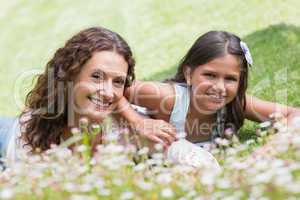 Happy mother and daughter lying on the grass