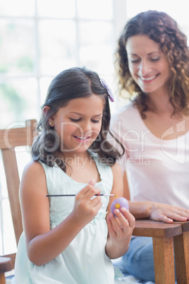 Happy mother and daughter painting easter eggs