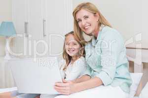 Happy mother and daughter using laptop