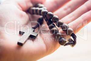 Hand holding wooden rosary beads