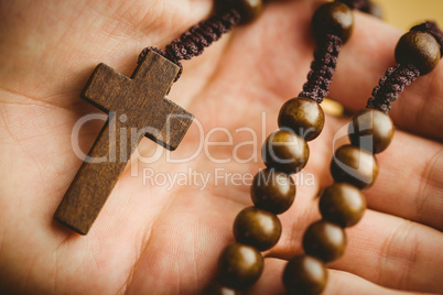 Hand holding wooden rosary beads