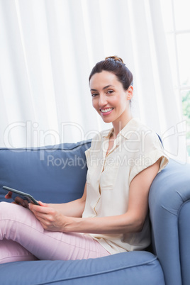 Casual brunette using tablet on couch