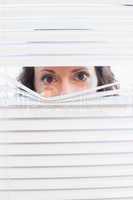 Curious woman looking through blinds