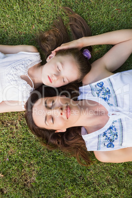 Mother and daughter lying on grass