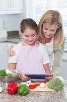 Mother and daughter cooking together with tablet pc