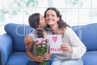 Cute girl offering flowers and card to her mother