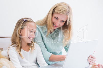 Happy mother and daughter using laptop