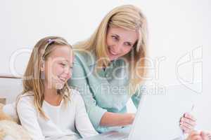 Happy mother and daughter using laptop