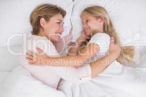 Mother and daughter cuddling in bed