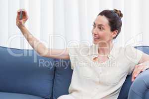 Casual brunette taking selfie on couch