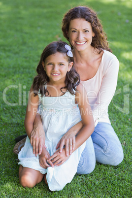 Happy mother and daughter sitting on the grass