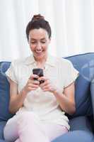 Casual brunette using phone on couch