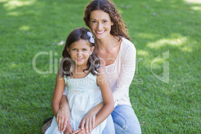 Happy mother and daughter sitting on the grass