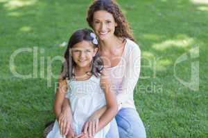 Happy mother and daughter sitting on the grass