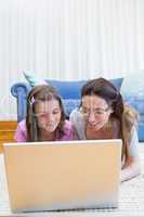 Mother and daughter using laptop on floor