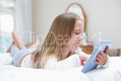 Little girl using tablet pc in the bed