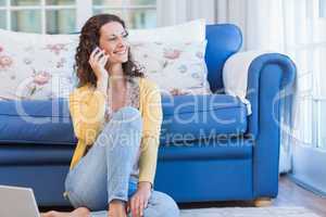 Pretty brunette sitting on the floor and speaking on the phone