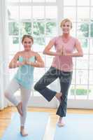 Mother and daughter doing yoga on fitness mat