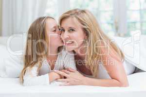 Daughter kissing her mother on the cheek in the bed