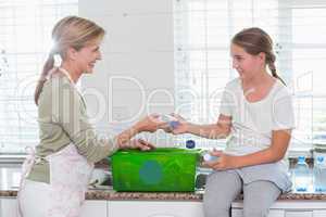 Mother and daughter putting bottles in recycling box
