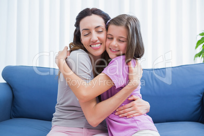 Mother and daughter hugging on couch