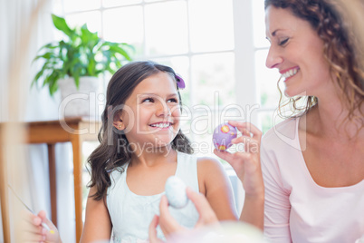 Happy mother and daughter painting easter eggs