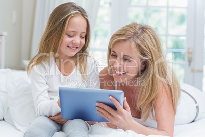 Mother and daughter using tablet pc in the bed