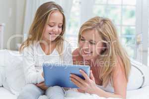 Mother and daughter using tablet pc in the bed