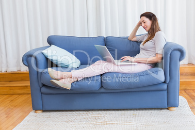 Casual woman using laptop on couch