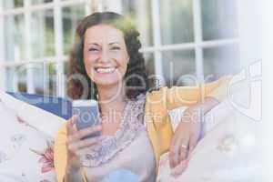 Pretty brunette relaxing on the couch with smartphone