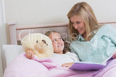 Happy mother and daughter reading a book