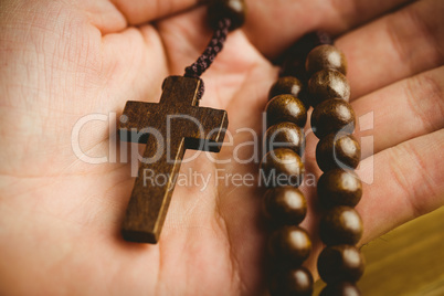 Hand holding wooden rosary beads