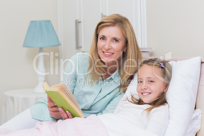 Happy mother and daughter reading a book