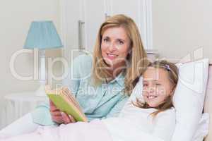 Happy mother and daughter reading a book