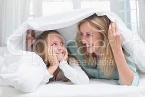 Mother and daughter looking at each other under the duvet