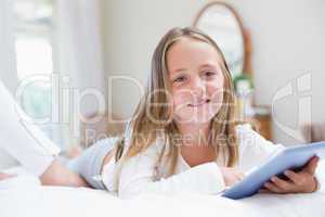 Little girl using tablet pc in the bed