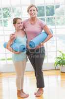 Mother and daughter holding yoga mats