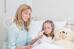 Mother giving her daughter cough medicine